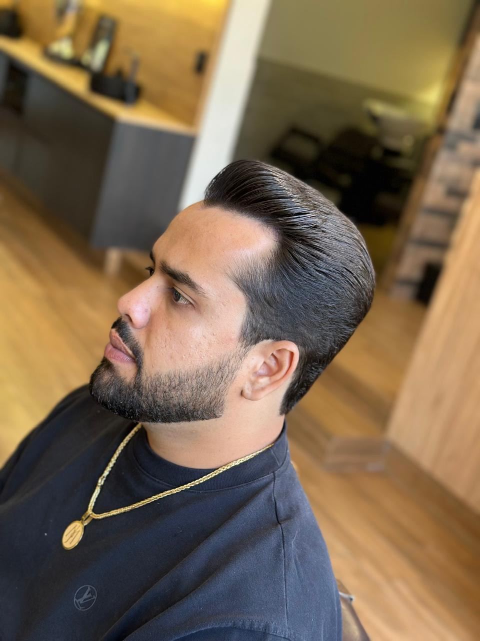 Cliente com cabelo penteado para trás e barba desenhada